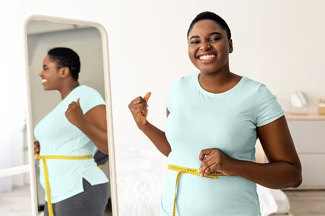 Persona sonriendo mientras se mide la cintura